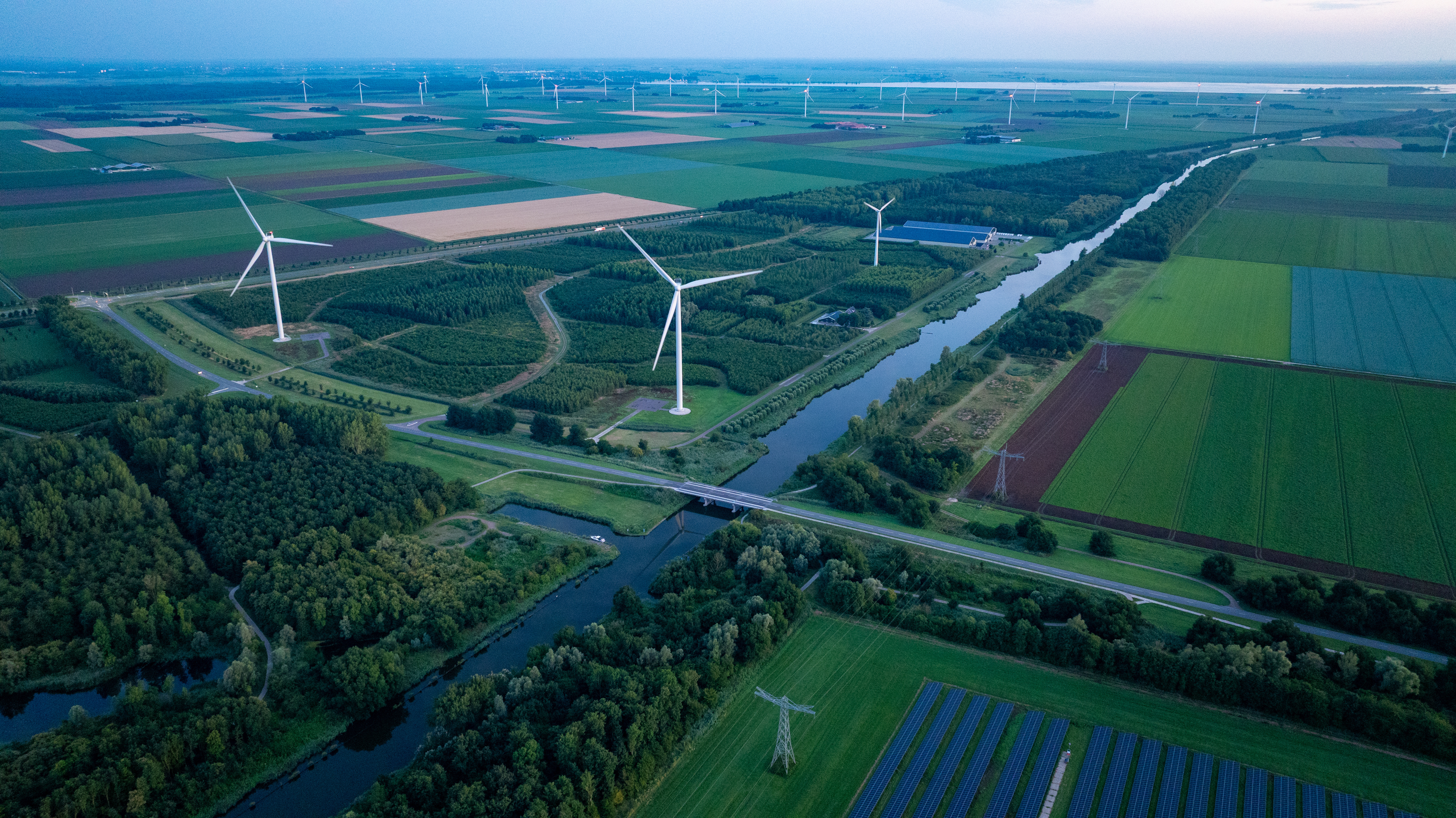 Aerial view of wind turbines and solar panels installed across agricultural land, representing institutional investment in renewable energy land acquisition in the Sun Belt and Appalachian Transition Zone
