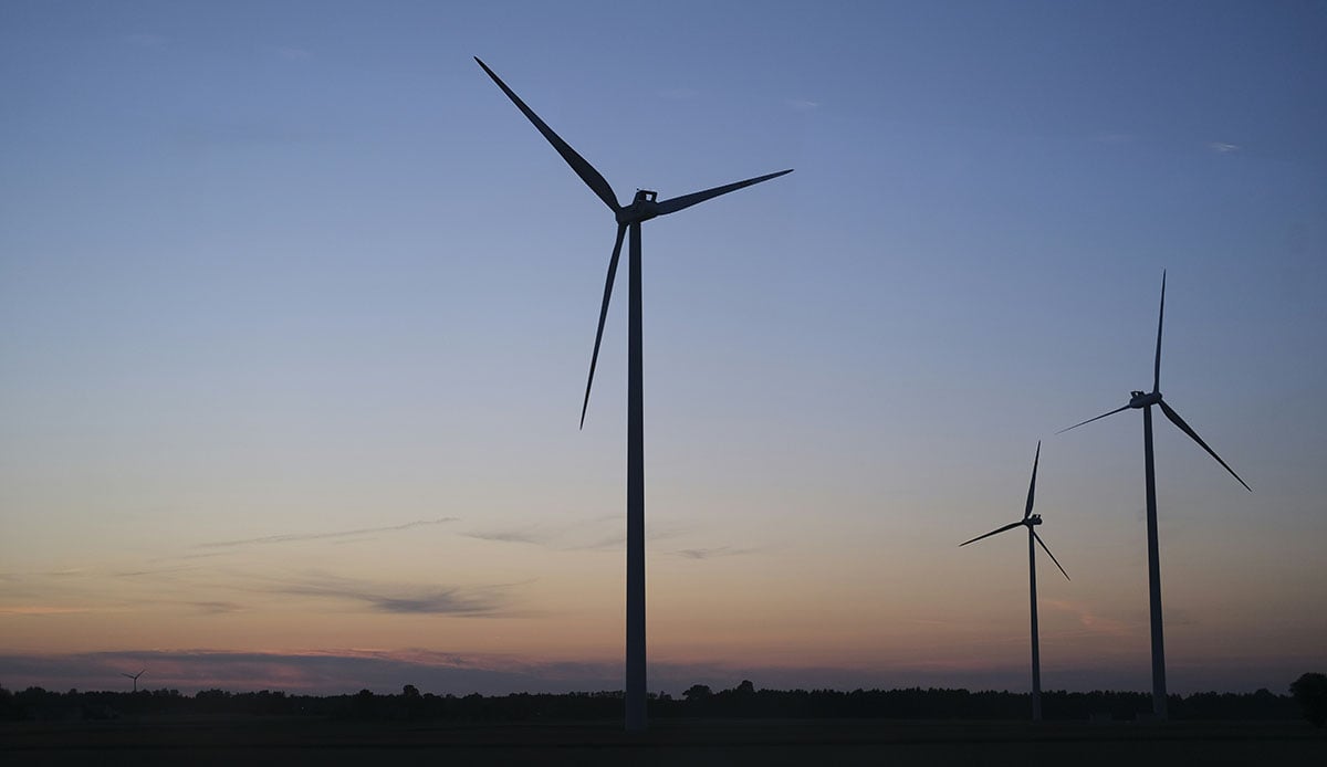 Row of operating wind turbines on US farmland - wind energy site selection and land lease opportunity