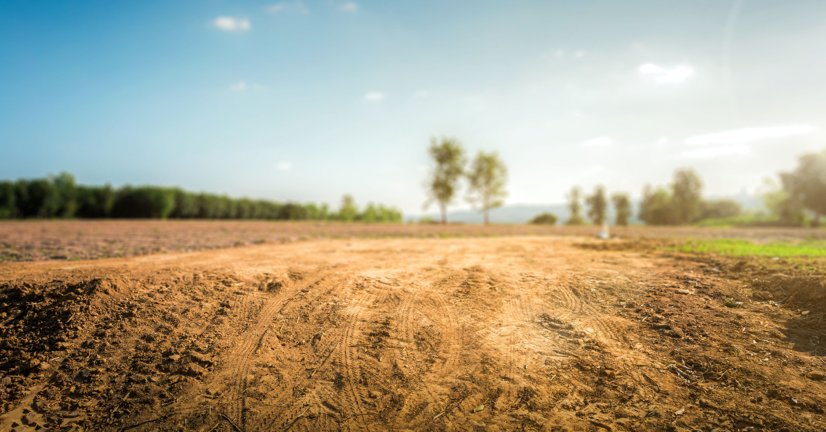 Bare agricultural land with tilled soil and open sky, representing the range of parcels land buyers and brokers value using methods like sales comparison, income approach, and residual land value analysis